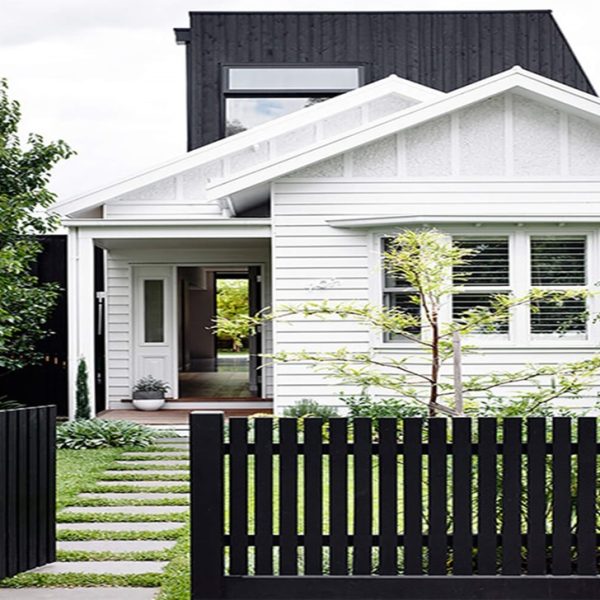This rich brown picket fence stands gracefully against a fresh green lawn.